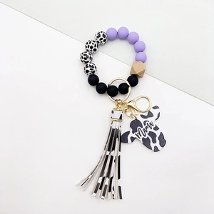 Close-up of Mama pendant with purple and black beads, cow print tassel on wristlet keychain