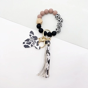 Detail of cow print wristlet keychain with Mama wooden bull head and tassel accent