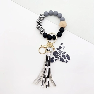 Detail of cow print tassel, wood beads, and butterfly charm with mama text engraving
