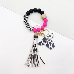 Detail of cow print wood bead keychain featuring pink accents and Mama engraved bull head