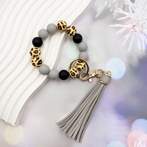 Close-up of silicone bead keychain with leopard print, grey tassel and gold metal clasp