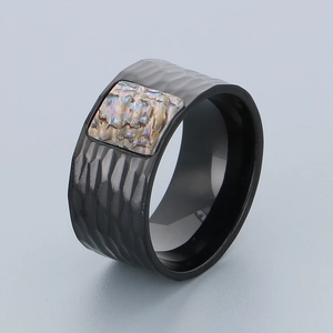 Macro detail of men's black hammered stainless steel ring with colorful abalone shell inlay
