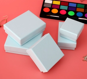 Stack of light blue matte jewelry boxes for rings and necklaces on coral pink background