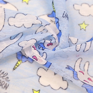 Detailed view of light blue dog vest fabric with unicorn prints and slub texture