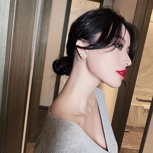 Hollow gold bow earrings with shimmering zircon stones worn by a model in close-up