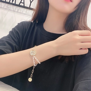Detailed view of elegant gold pearl bracelet featuring a crystal-inlaid coin pendant