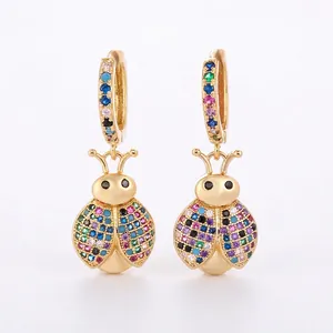 Close-up of golden ladybug earrings featuring multi-color zircon pavé settings