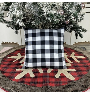 Detail of black and white checkered pillow cover on festive red reindeer tree skirt