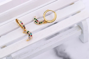 Detail of gold crescent moon hoop earrings with colorful rainbow cubic zirconia stones