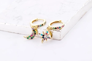 Detailed macro view of gold moon and star earrings set with colorful cubic zirconia stones