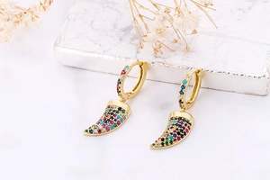 Detailed view of gold earrings with multicolored cubic zirconia in a crescent horn design
