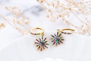 Detailed close-up of gold sunburst drop earrings featuring colorful zircon stones