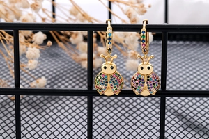 Detailed view of gold hoop earrings with ladybug charms and multi-colored cubic zirconia