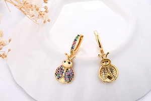 Detail of gold ladybug earrings with colorful zircon inlay and honeycomb back