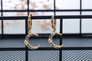 Macro detail of gold moon earrings with colorful cubic zirconia and white main stone