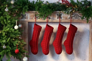 Close-up of four red knitted Christmas stockings with cable pattern hanging on fireplace