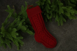 Macro view of red cable knit Christmas stocking with classic pattern on dark texture