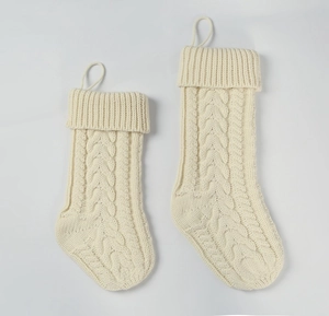 Detail of two cream knitted Christmas stockings with classic cable knit pattern and loops