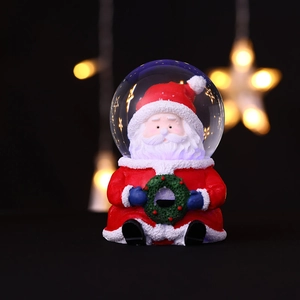Gros plan d'une figurine de Père Noël en résine dans une boule à neige avec lumière chaude