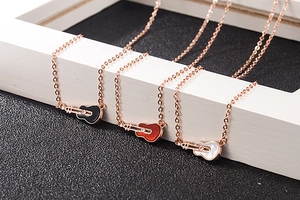 Detailed macro shot of three guitar pendant necklaces in red, black, and white mother-of-pearl