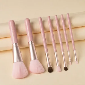 Detail of 7-piece pink makeup brush set with rose gold ferrules on beige paper