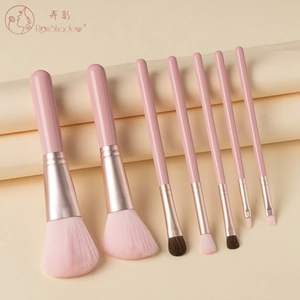 Detail of 7-piece pink makeup brush set with rose gold ferrules on beige paper