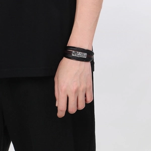 Detail of multi-layer braided leather bracelet for men with nautical compass metal clasp