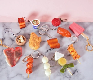 Detailed close-up of PVC simulation food keychains featuring steaks and noodles