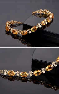 Macro detail of gold bracelet featuring oval citrine gems and clover diamond accents