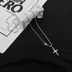 Minimalist silver cross necklace with center gemstone on a white pedestal display