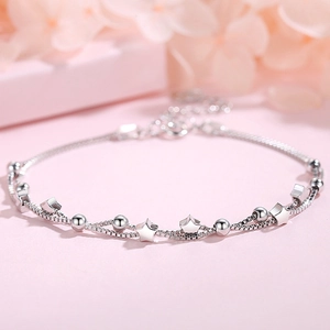 Double-layered 925 sterling silver star bracelet with round beads on a soft pink background