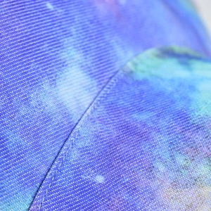 Detailed close-up of blue and purple tie-dye fabric with reinforced stitching on bucket hat