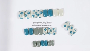 Détail de faux ongles fleurs bleu gris Morandi avec finition brillante sur support blanc
