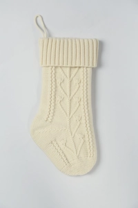 Detail of cream cable-knit Christmas stocking with hanging loop and ribbed cuff texture