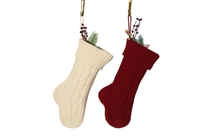 Close-up of red and beige knitted Christmas stockings with pine and berry decorations