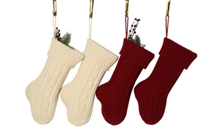 Close-up of four knitted Christmas stockings in cream and red with festive berries