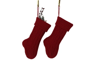 Close-up of red cable-knit Christmas stockings with festive red berries and pine branches