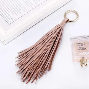 Porte-clés à franges en similicuir rose avec anneau doré sur un décor de bureau chic