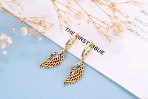 Macro detail of gold wing earrings with colorful zircons and intricate hollow design