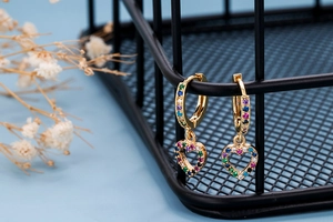 Macro detail of gold-plated hoop earrings with multi-color zircon heart pendants