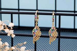 Detail of gold angel wing hoop earrings with vibrant colorful cubic zirconia crystals