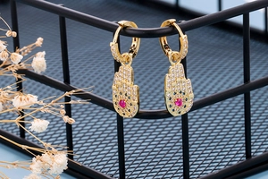 Detailed macro view of golden Hamsa Hand earrings with colorful zircon stones on display