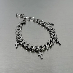 Silver Cuban link bracelet with four cross pendants on a brushed metallic background