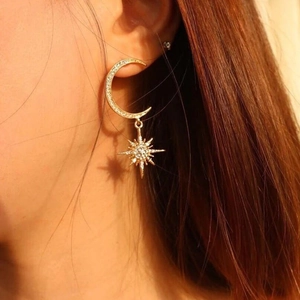 Close-up of elegant gold crescent moon and star drop earrings on a female model