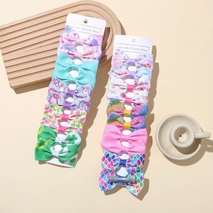 Flat lay of 14 handmade ribbon hair clips with unicorn and rainbow patterns on cards