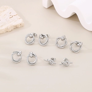 Macro detail of four pairs of polished silver titanium steel interlocking knot earrings