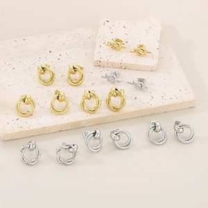 Macro detail of intertwined gold and silver twisted knot stud earrings on stone