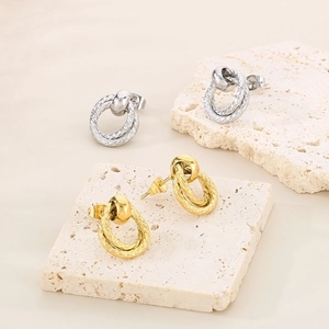 Detail of interlocking gold and silver double-hoop earrings with snake texture pattern
