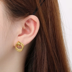 Detailed close-up of double-loop gold earrings with elegant twisted texture on ear