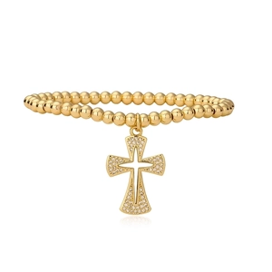 Detailed macro view of golden beaded bracelet with shimmering zircon cross pendant